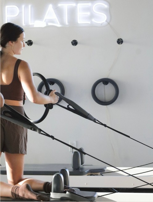 Instructor under the PILATES neon sign